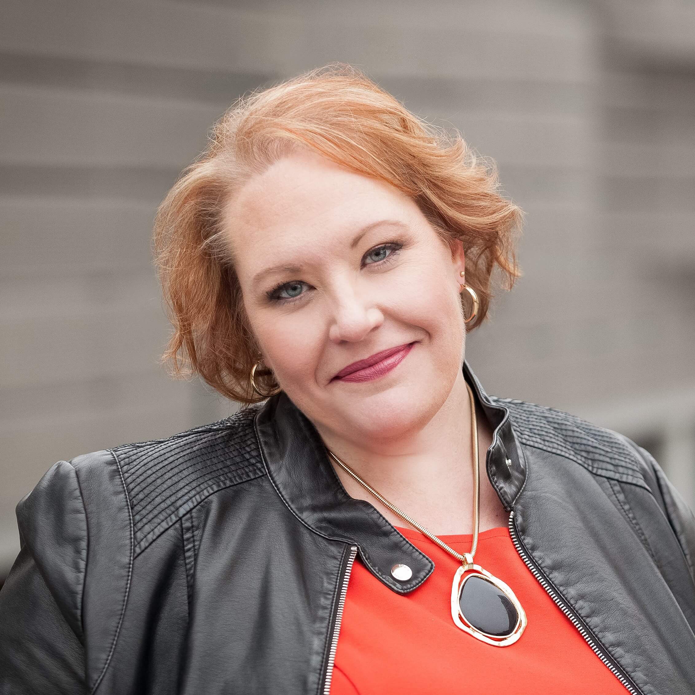 Headshot for Cherity Koepke in a red shirt and black jacket