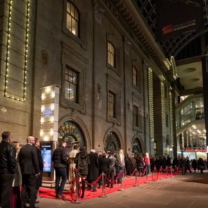 A long queue of patrons walk the red carpet in front of the Ellie Caulkins Opera House