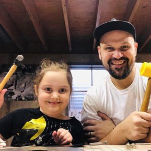 Man poses with daughter, playing with toy mallets