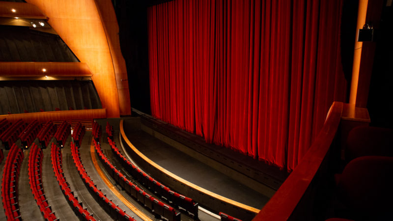Inside the Ellie Caulkins Opera House with the red velvet curtain lowered.