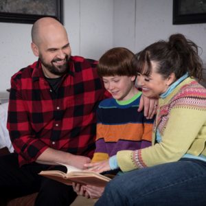 The momentarily happy Torrance family sits together reading a book