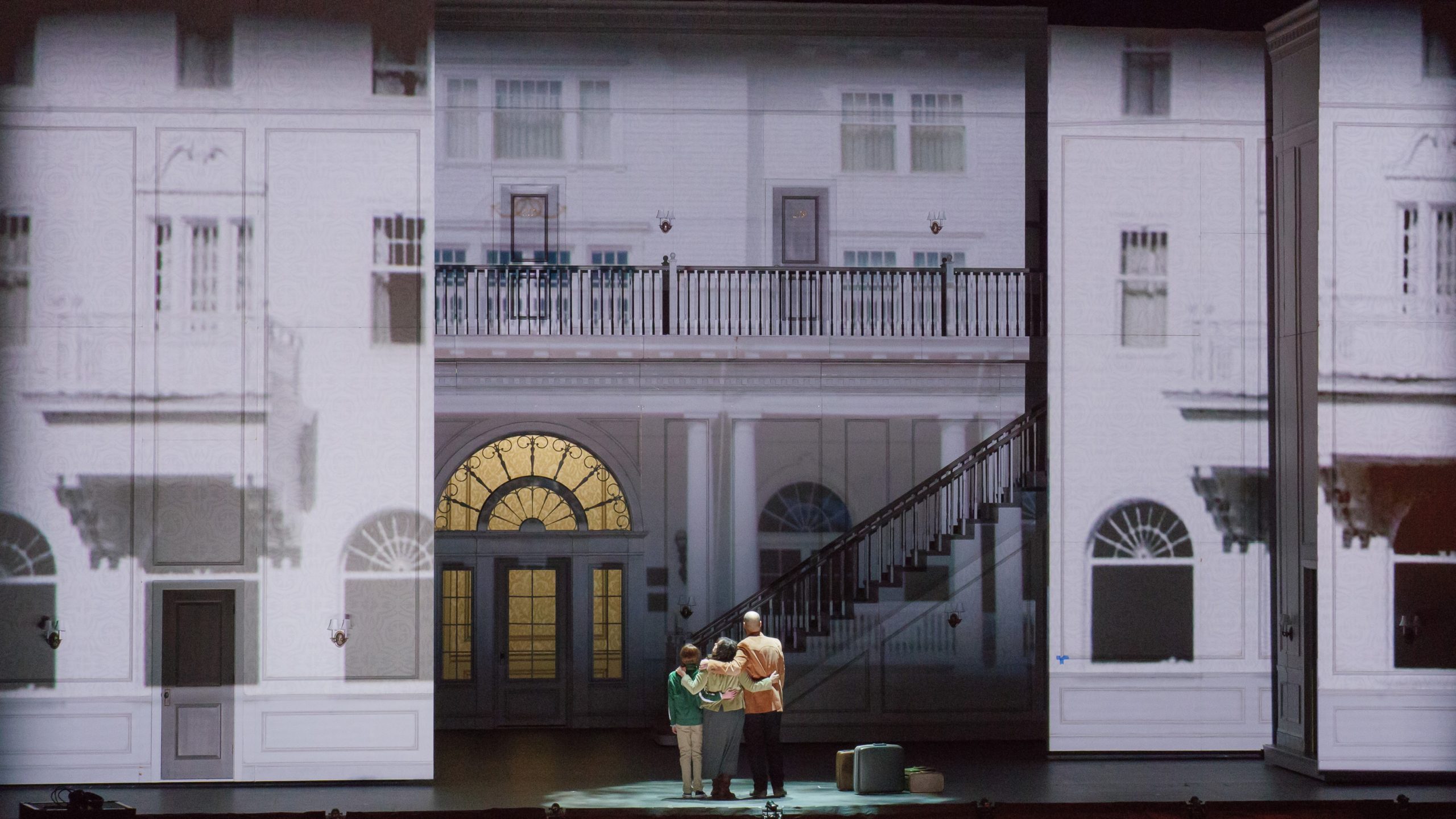 The Torrance family stands backs to audience and embraces as they take in The Overlook Hotel.