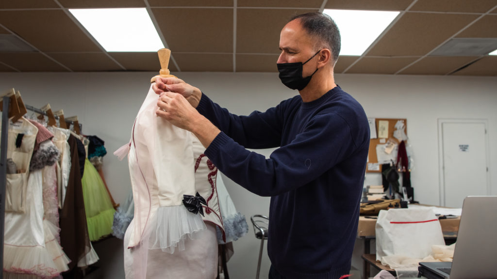 A man making stitches on a dress.