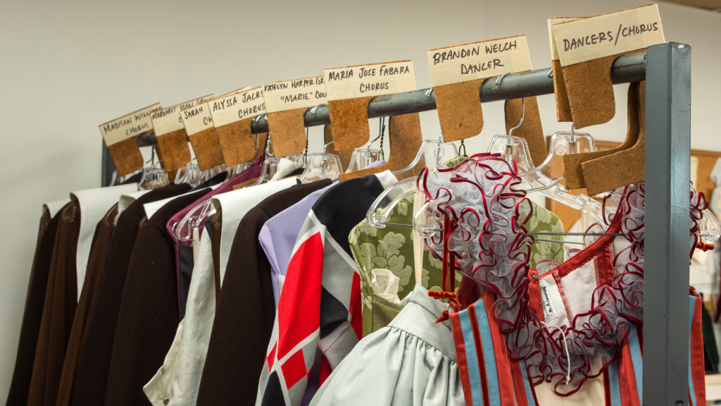 A row of costumes on a clothing rack