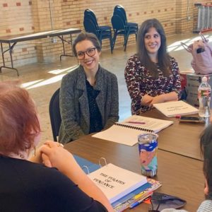 Artists in Residence sit around a table with the musical score to Pirates of Penzance in front of them