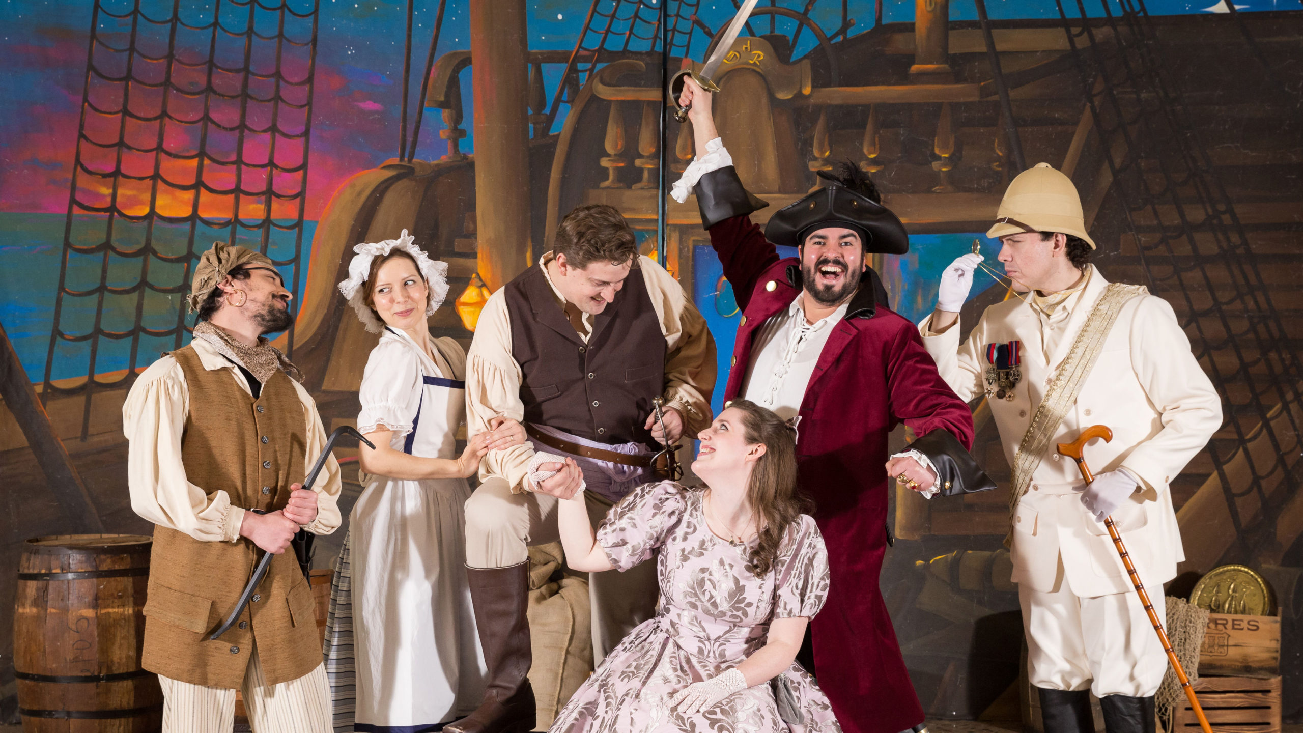 The cast of The Pirates of Penzance poses in front of the ship set