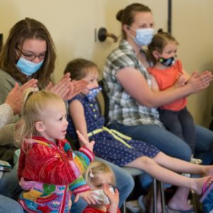 Children and caregivers applaud for an Artist in Residence performance.