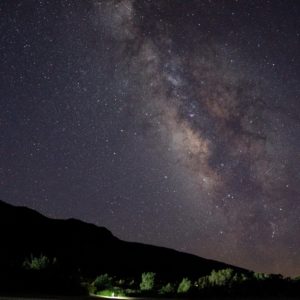 A spectaular starlight night sky fills the image above the black of the dunes at night.