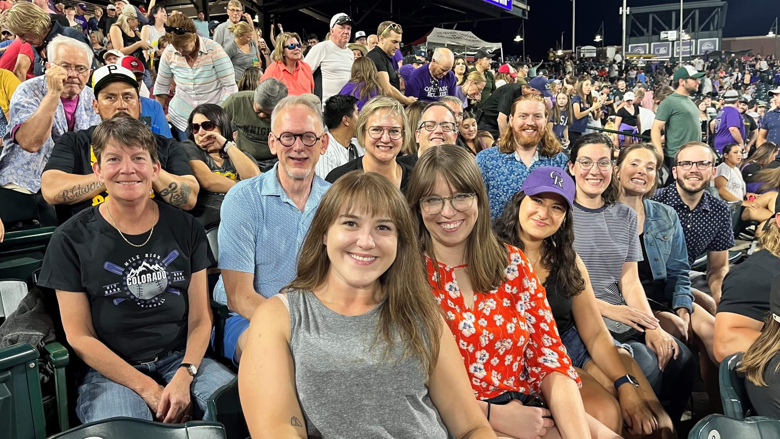 Two rows of people sit in a populated stadium.