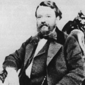 A grainy black and white photograph shows an adult Francesco Maria Piave sitting in an ornately carved wooden chair.