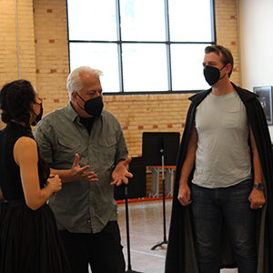 Three masked individuals work together in rehearsals.