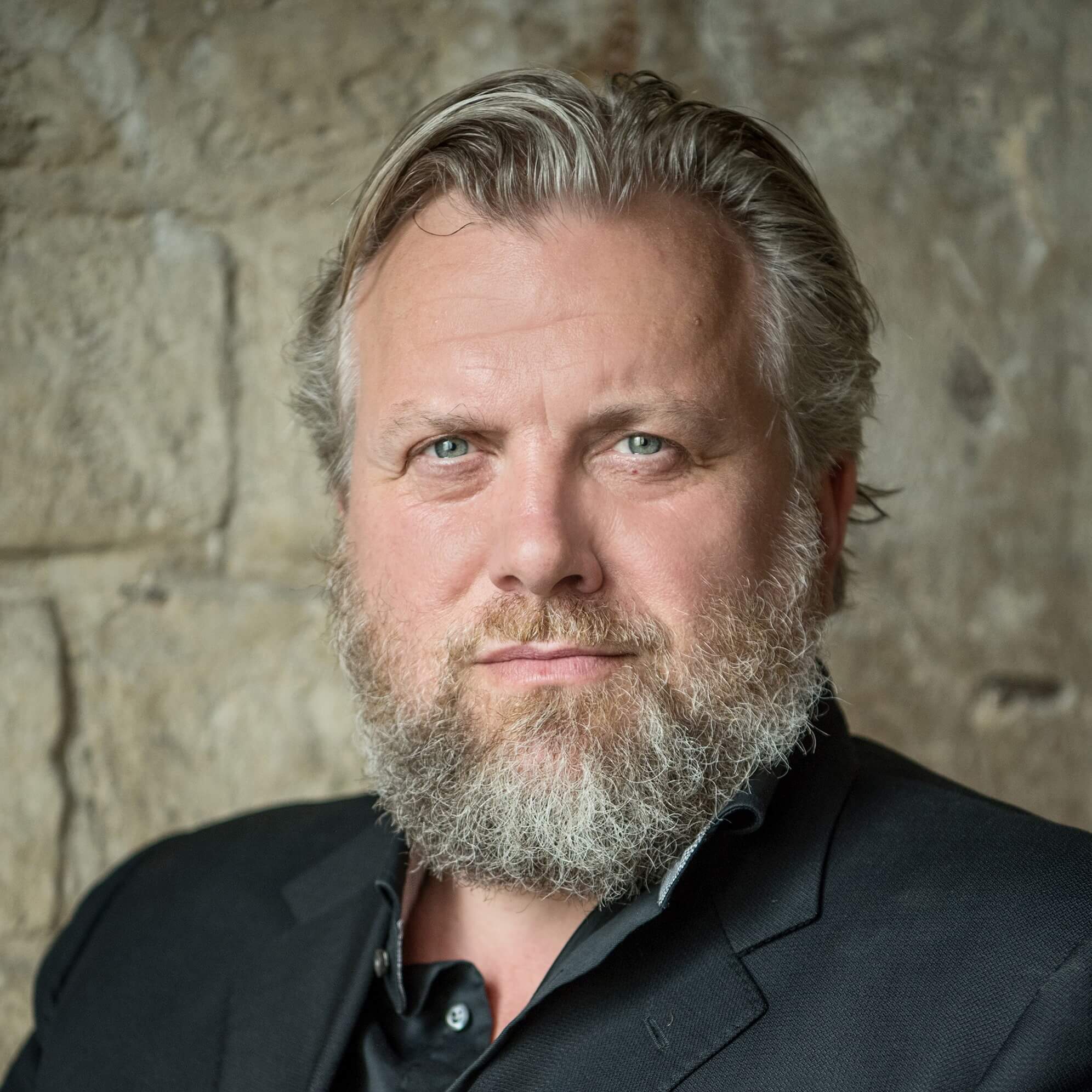 Headshot of a man with a short beard and blue buttom up shirt