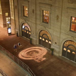 A tan building with the Opera Colorado logo on the ground in front