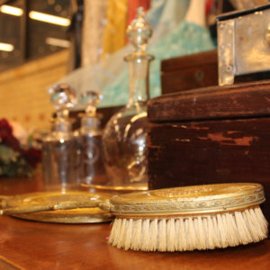 Items including a brush, bottles, and flowers sit on a table