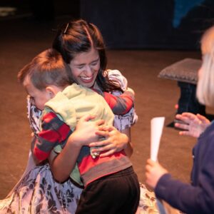 A young boy and a woman sitting on the flood share a hug