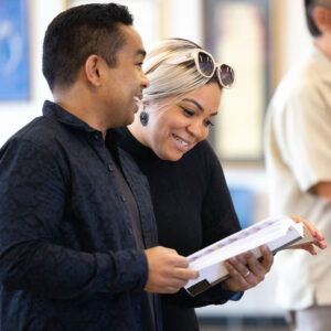 A man and woman smile as they look at the sheet music they are sharing