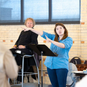 A woman in a blue shirt directs a group of people