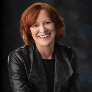 Headshot of a woman wearing all black with red hair