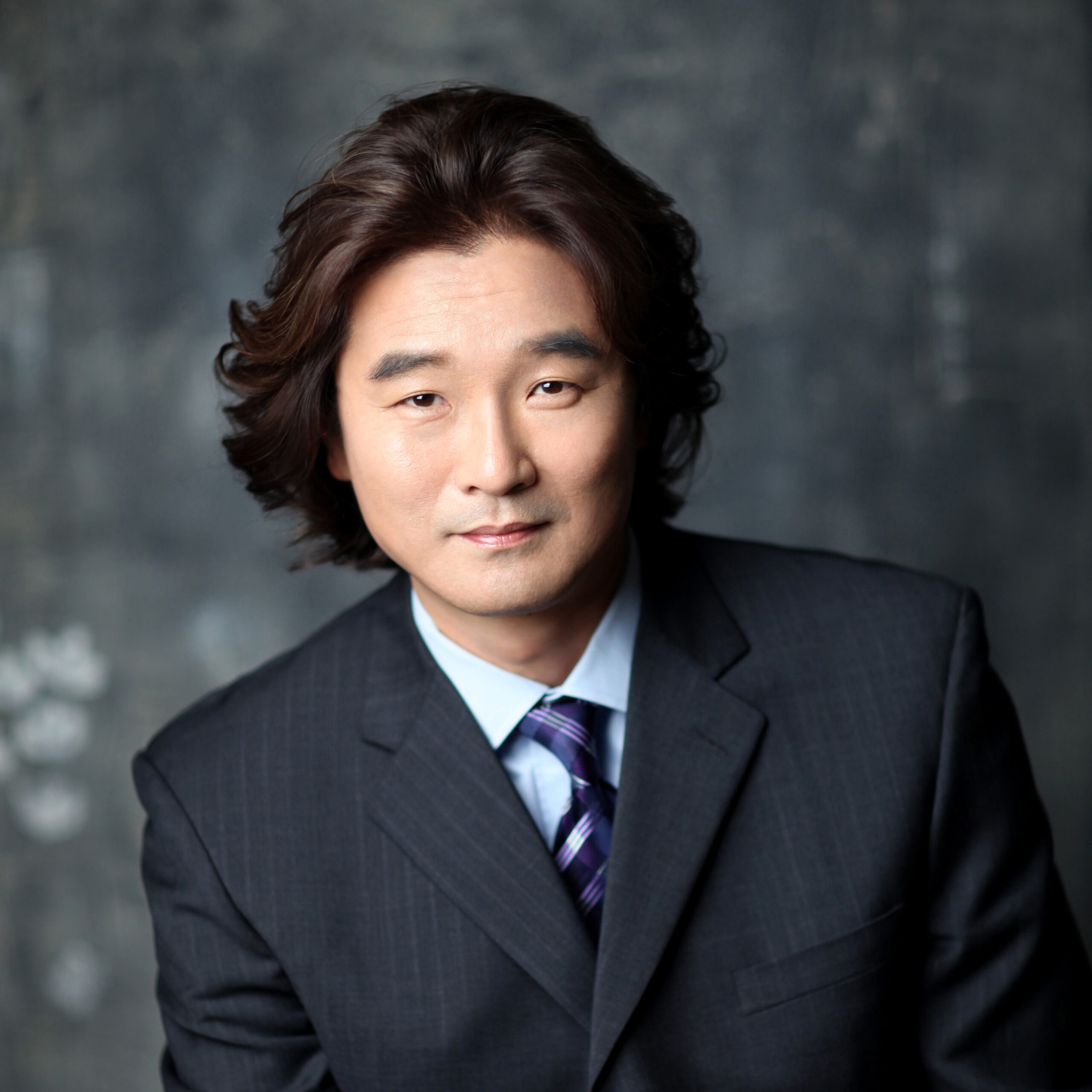 HEadshot of a man with dark hair and a dark navy suit