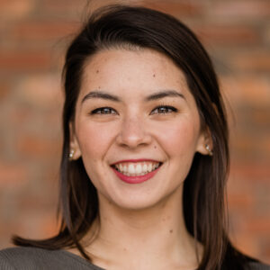 A woman with dark hair faces the camera smiling