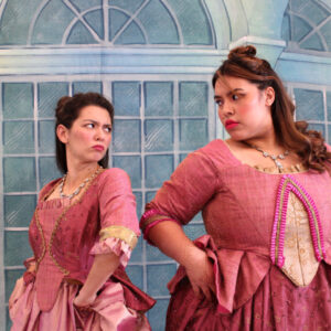 The Artists in Residence playing the step-sisters glare at each other in their pink dresses.