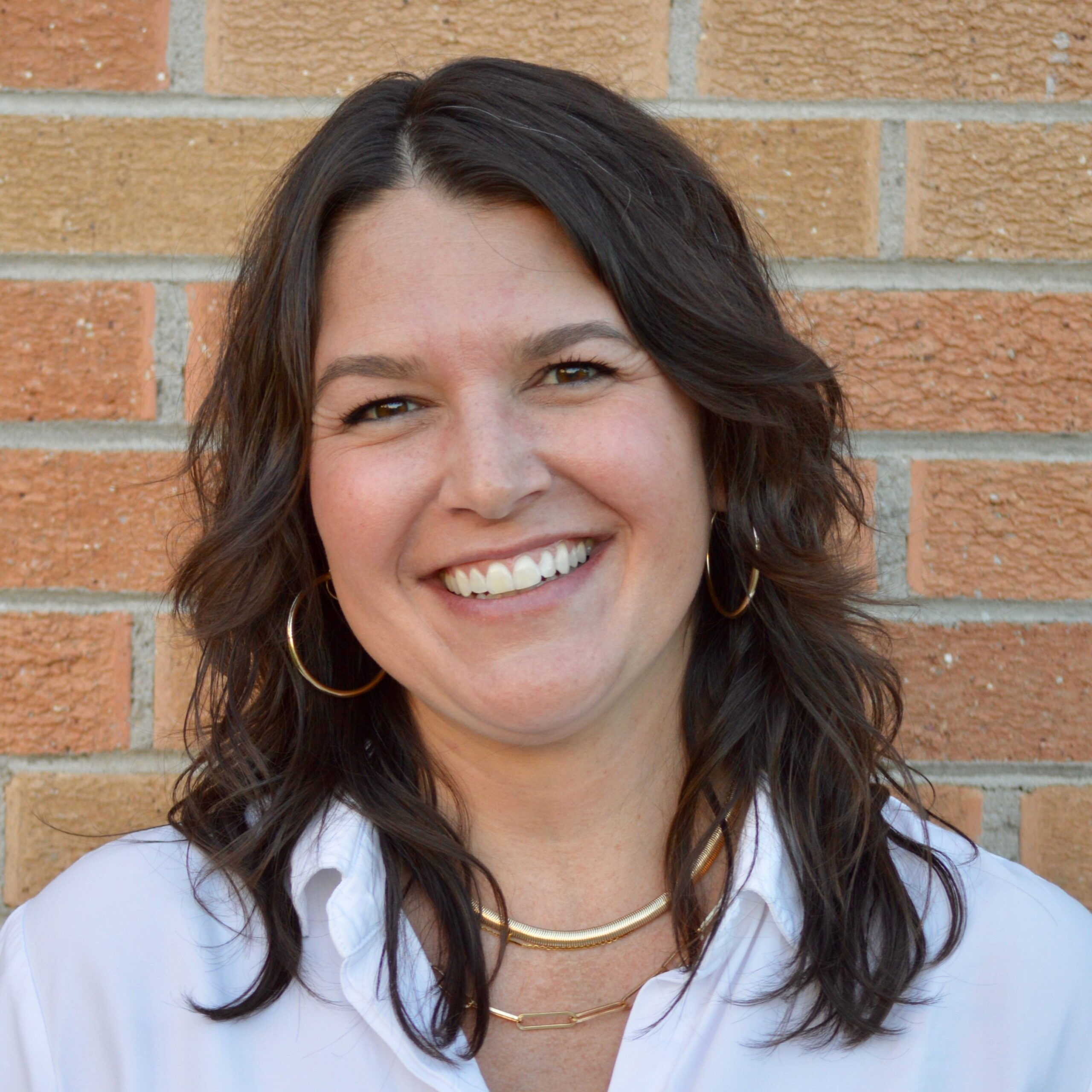 A white woman with brown hair smiling