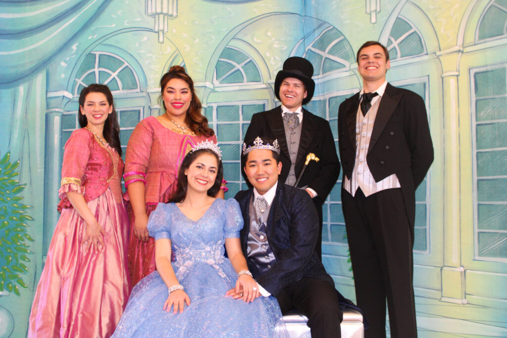 A group of people gather, two women in pink dresses, one in dlue, three men in suits