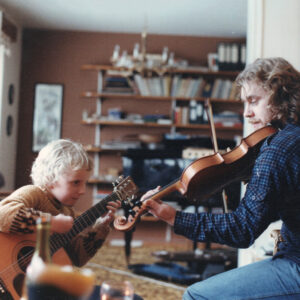 A gound boy plays the piano with his father who plays the violin