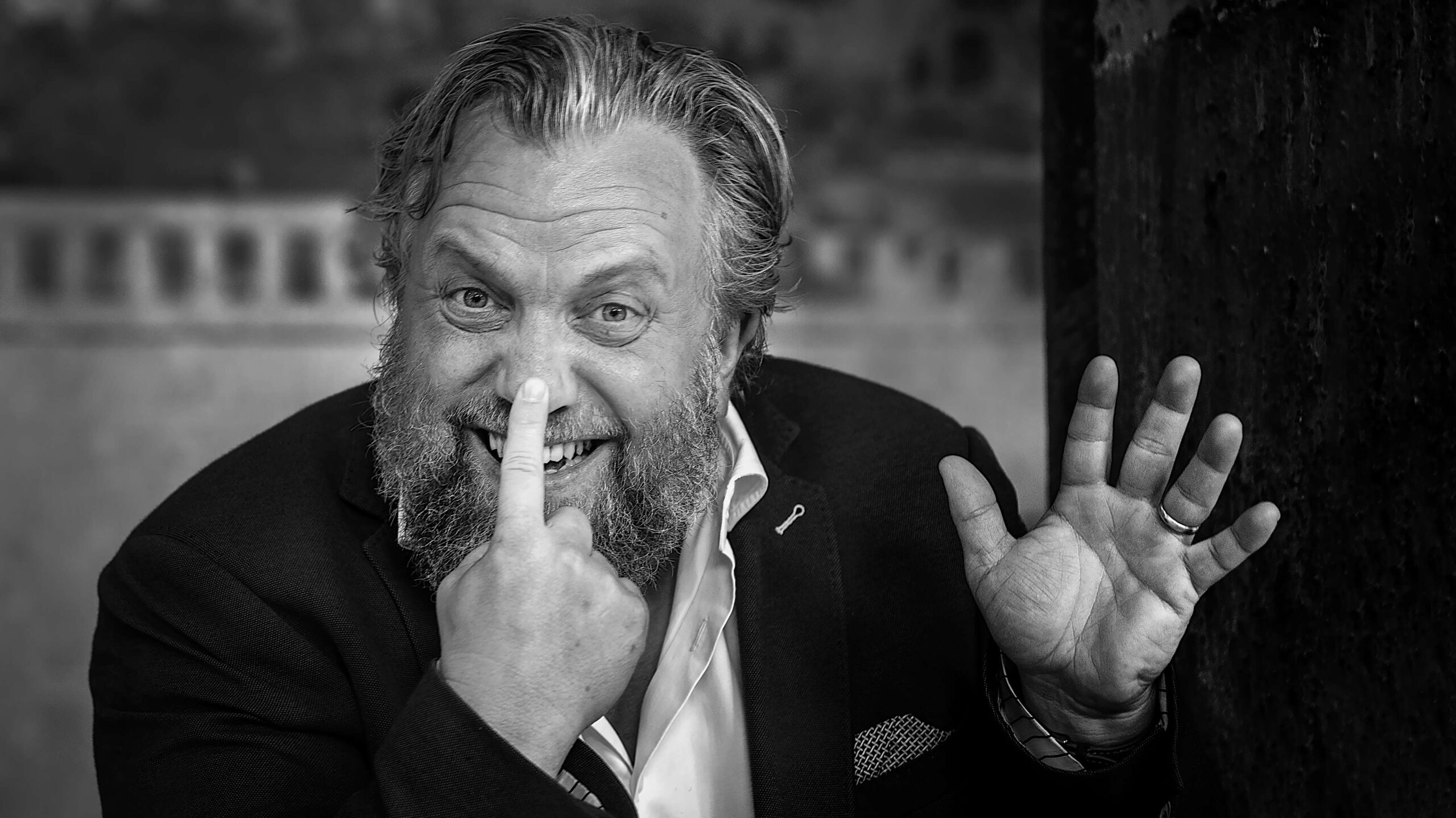 Black and white photo of a man tapping his nose with a finger