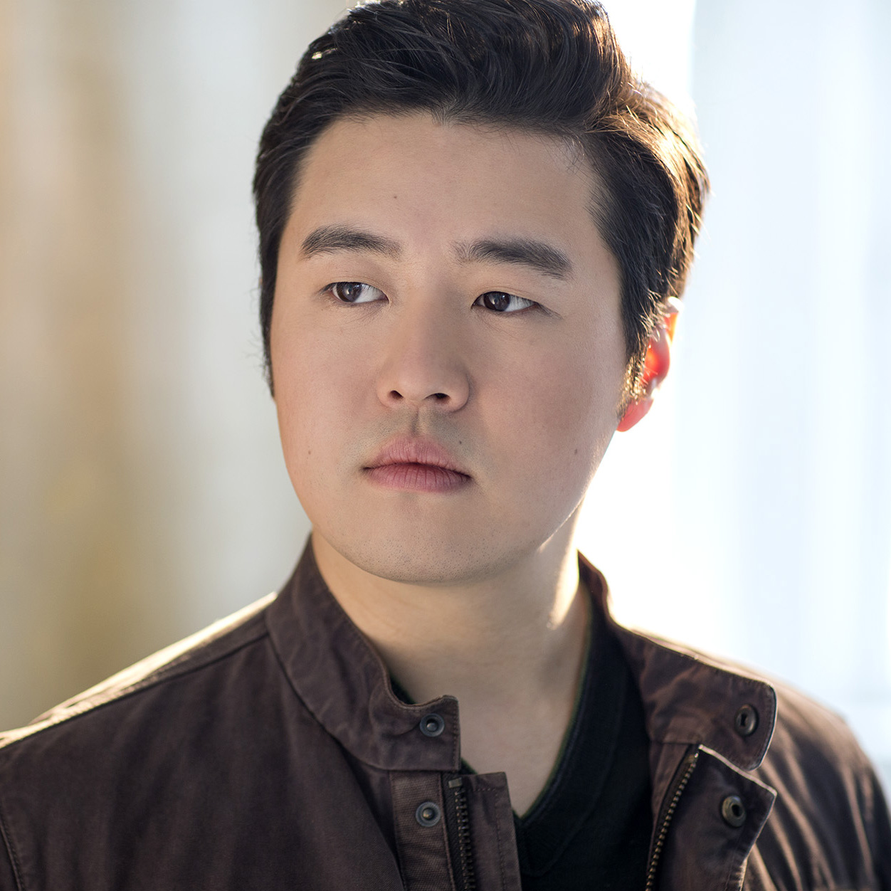 Headshot of a man with dark hair and a brown shirt