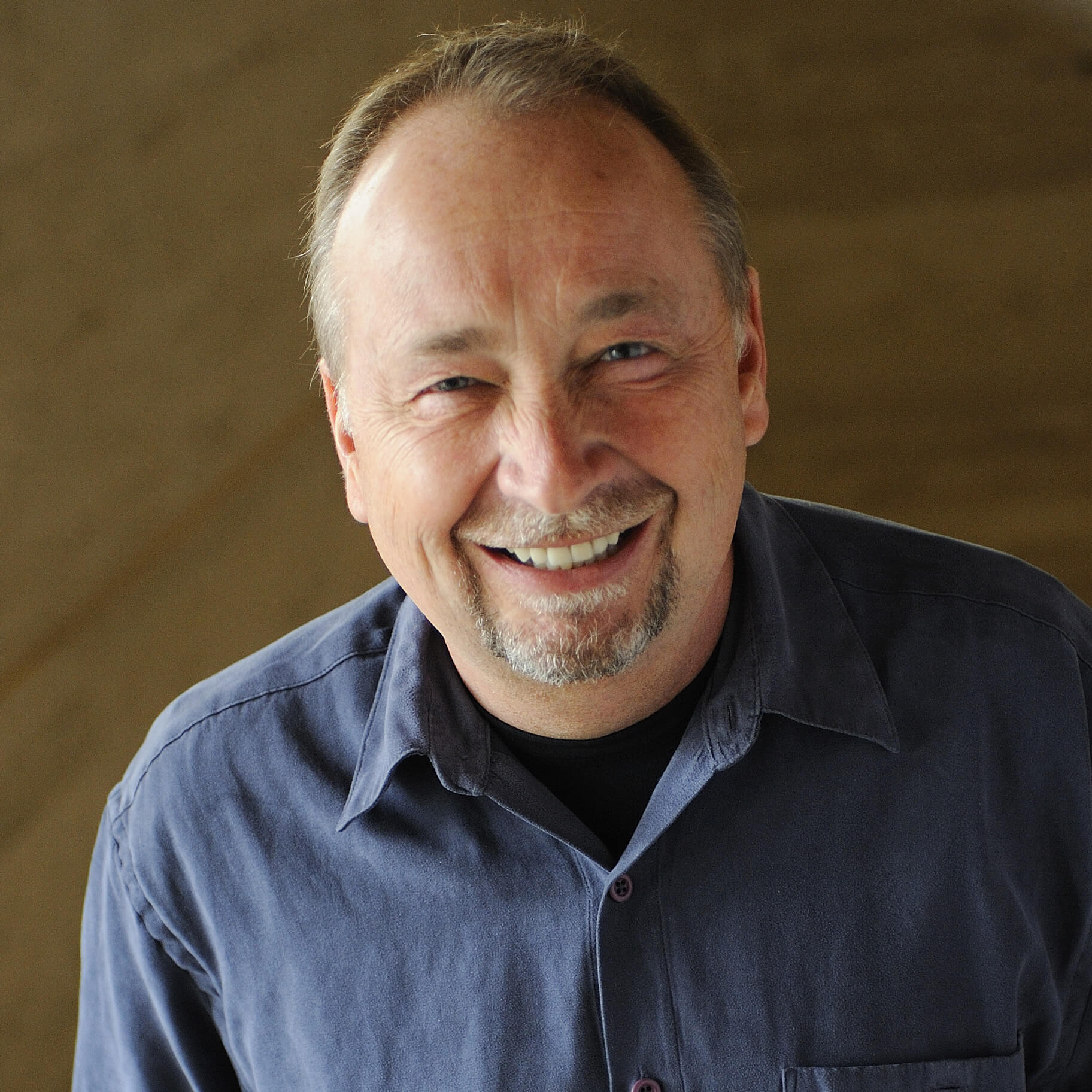 Headshot of a mean with a bead wears a blue shirt