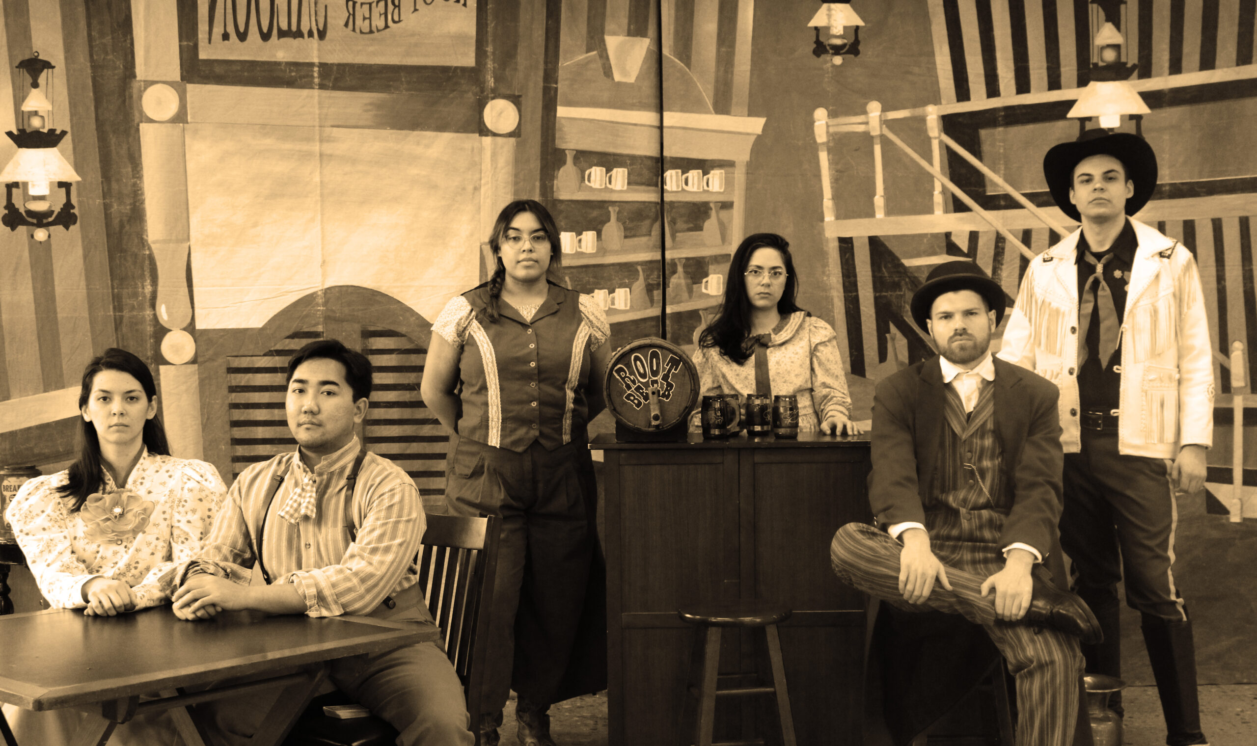 An old West style photo of a group of people sitting and standing in a saloon
