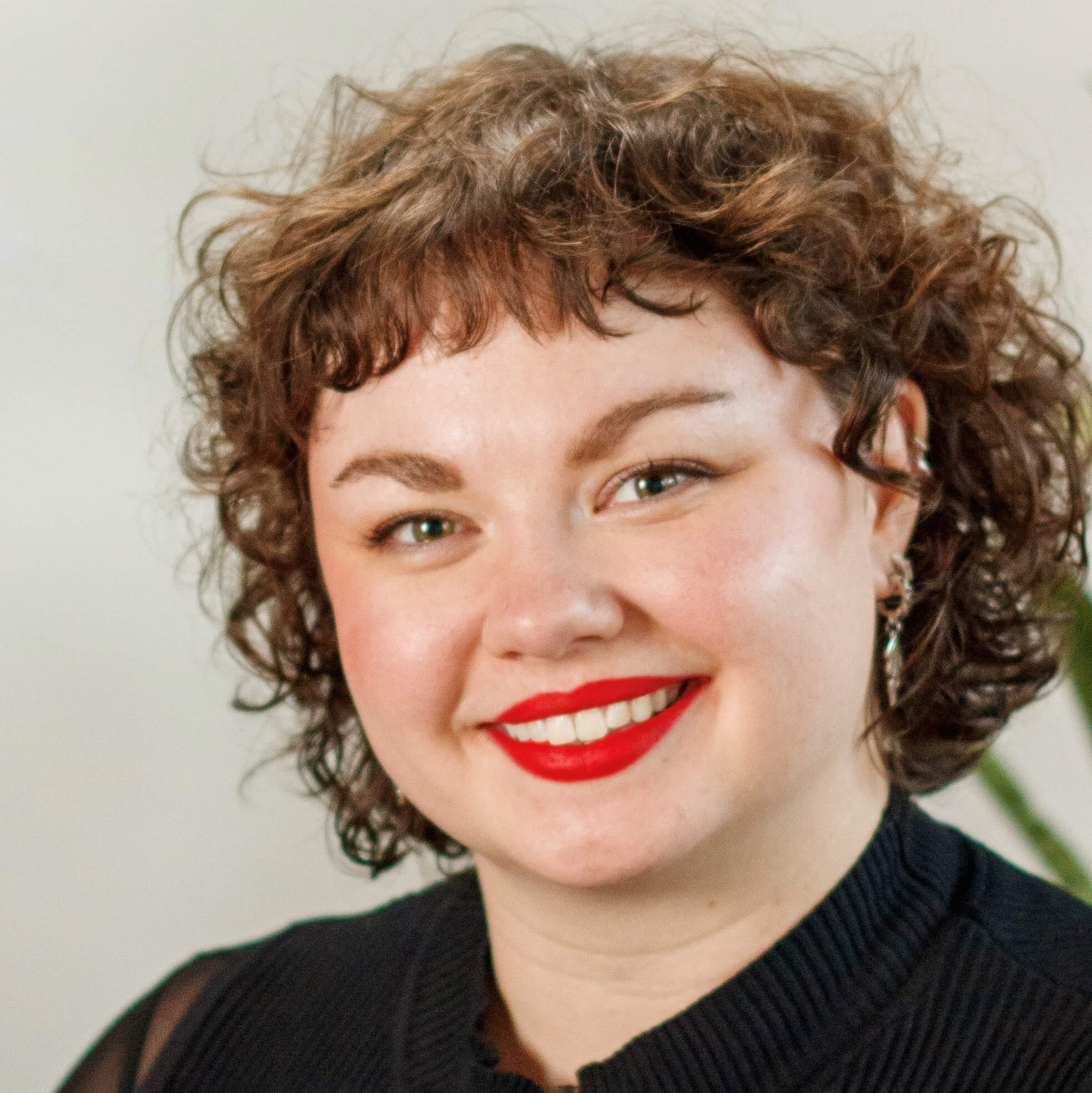 A woman with curly light brown hair smiles at the camera