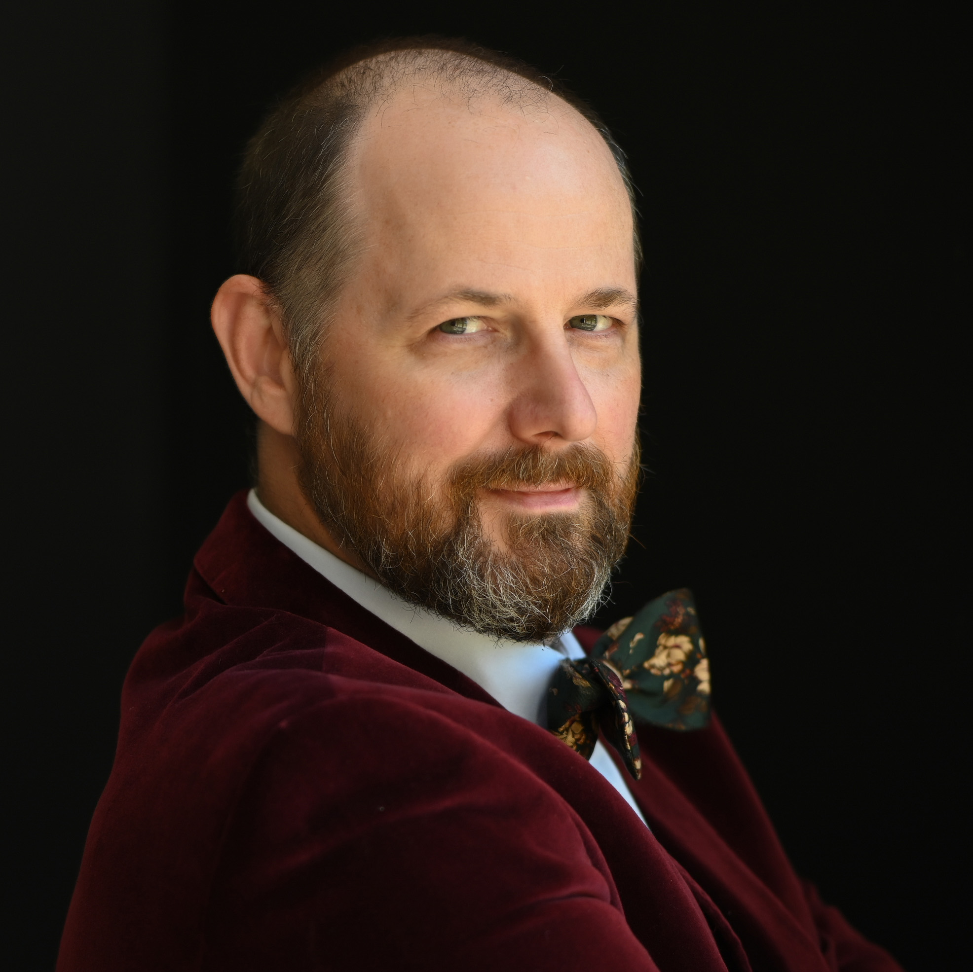 Headshot of a man with a brown beard and red jacket