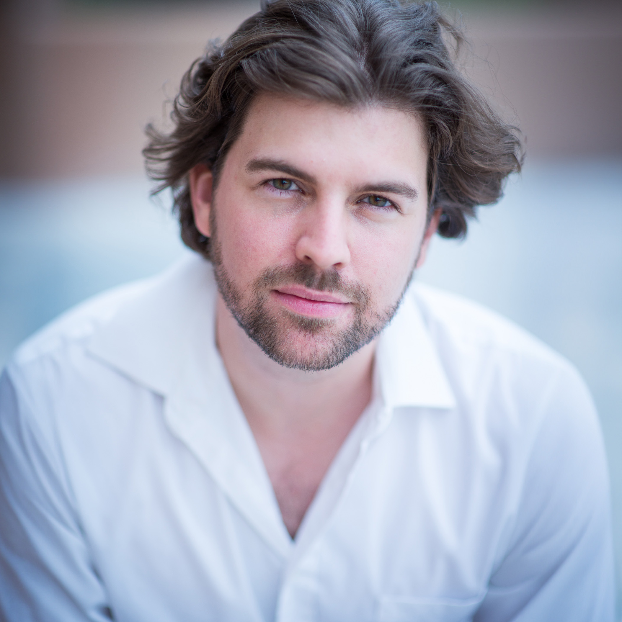 HEadshot of a man with brown hair and dark eyes wearing a white shirt.