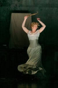 Woman in white dress dancing with a braid in her hand.